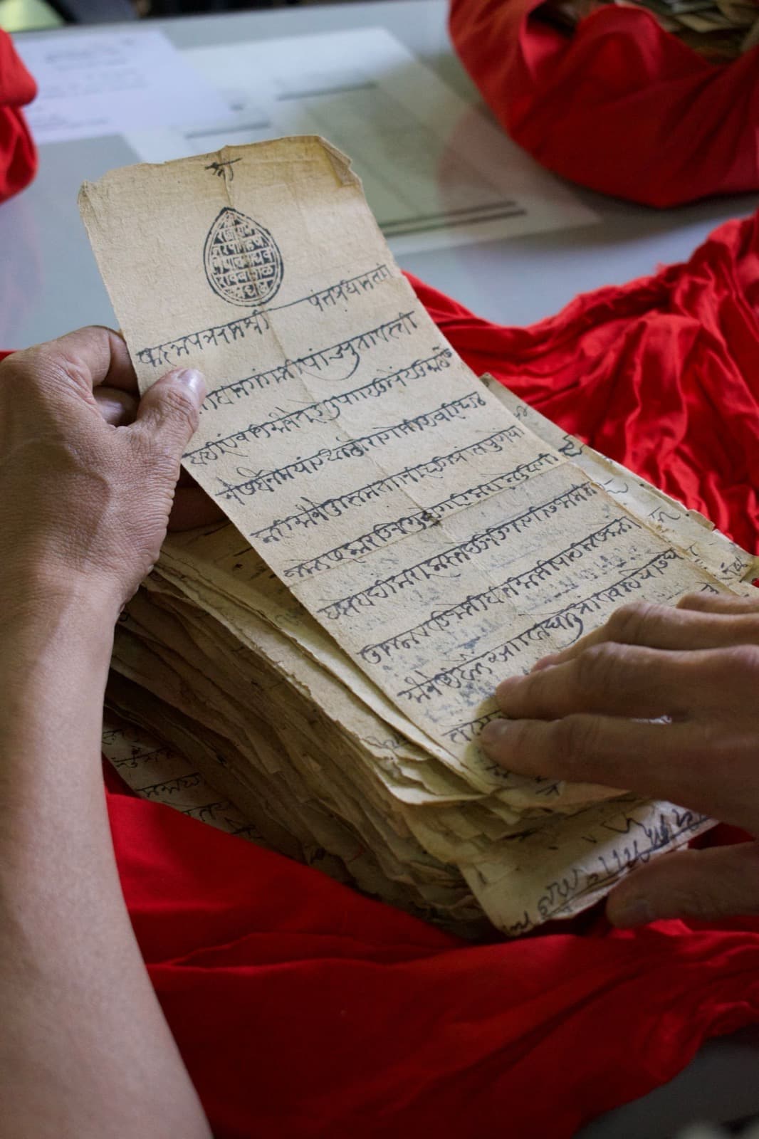 Hands turning the pages of a handwritten Sanskrit manuscript